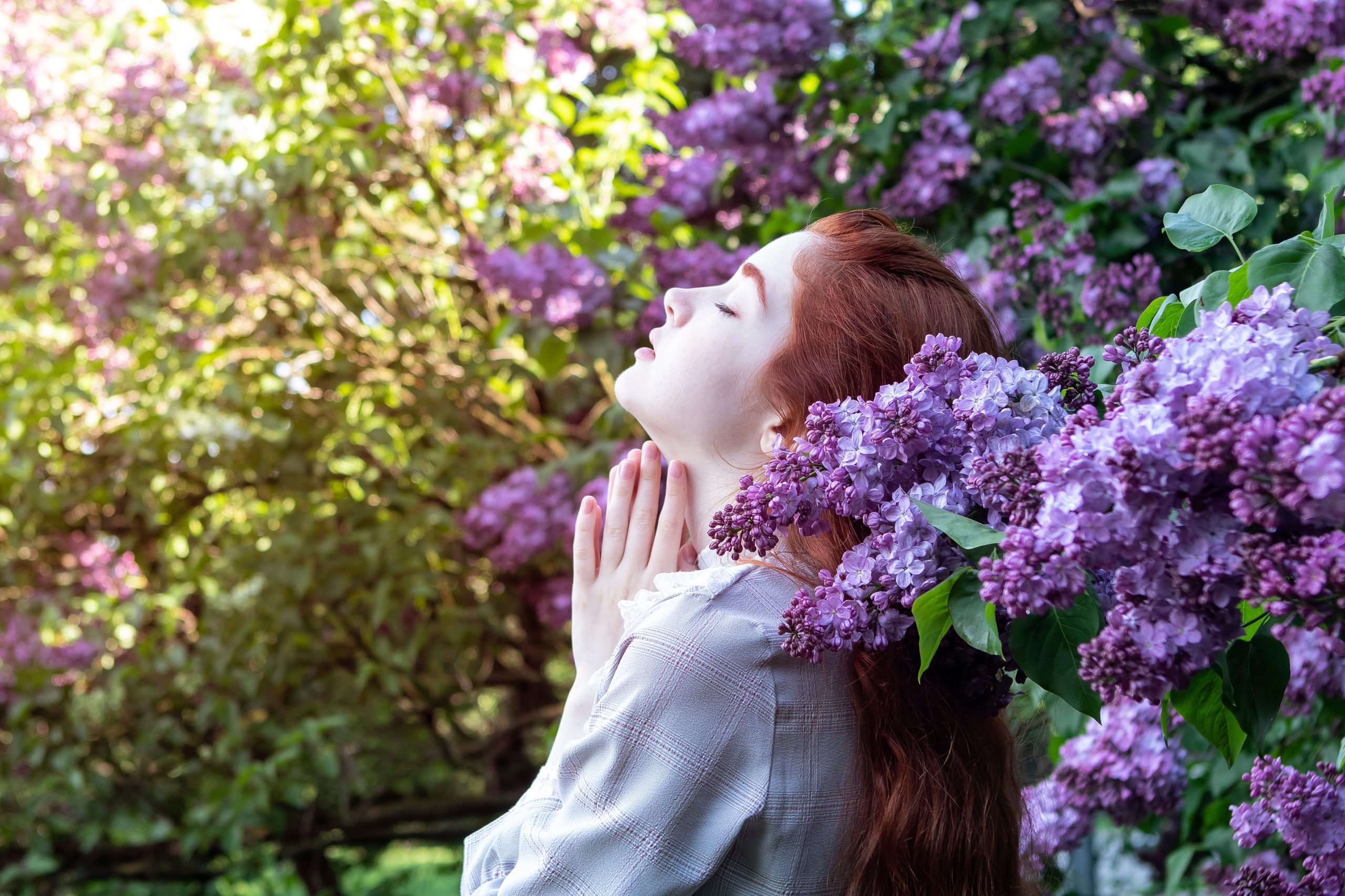 A woman stands gracefully before a tree adorned with vibrant purple flowers, creating a picturesque scene.